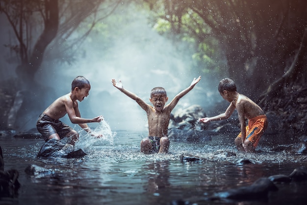 Happy boys has fun playing in the creek, Thailand countryside