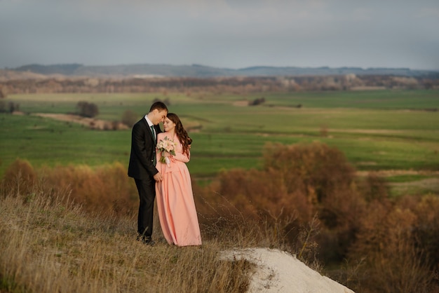 Happy bride and groom walking on a hilly area with a beautiful view.