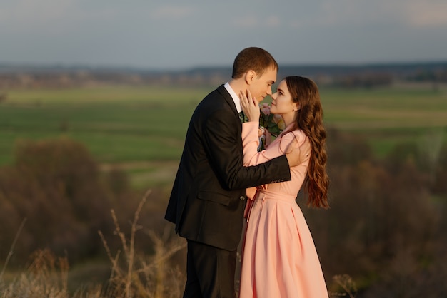 Happy bride and groom walking on a hilly area with a beautiful view.