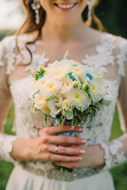 Happy bride holds a wedding bouquet of white roses