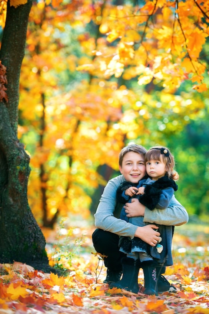 Happy brother and sister are sitting on the bench talking and laughing. In nature, walk in the open air.