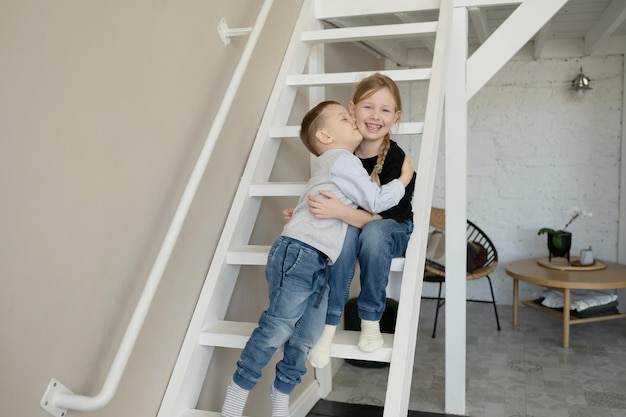 Photo happy brother and sister of preschool age, laughing and hugging, at home.