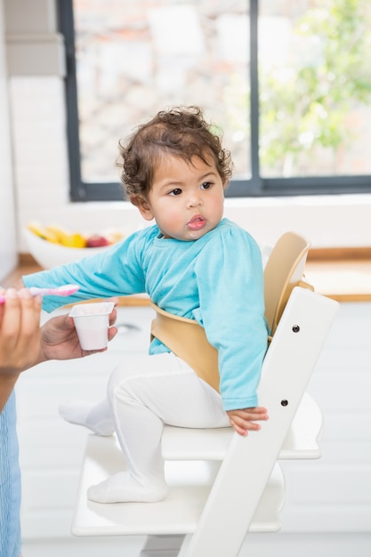 Happy brunette feeding her baby in the kitchen