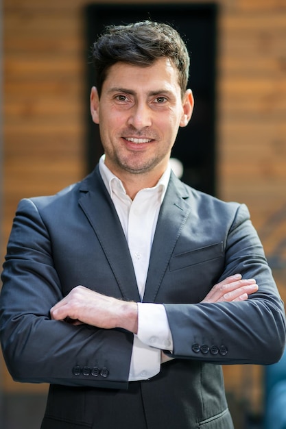 Happy brunette man smiling at the camera cross his hands in the office