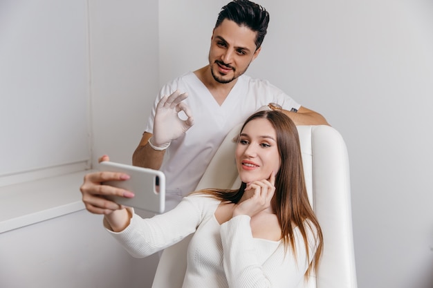 Happy brunette woman at beauty medical clinic. She is talking with doctor about face esthetics treatment.