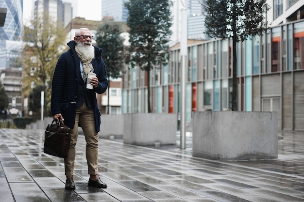 Happy business hipster elderly man walking to work in  city - Focus face