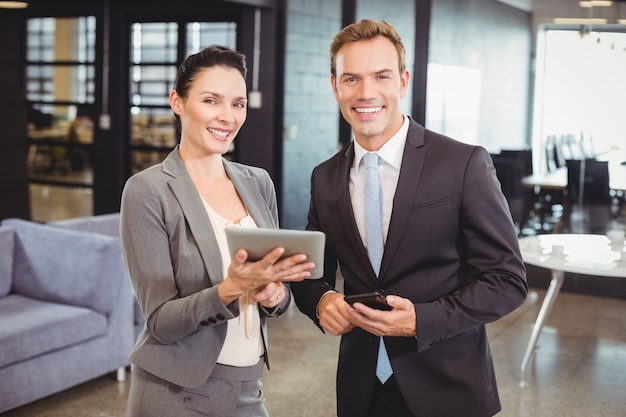 Happy business man and business woman with digital tablet and mobile phone