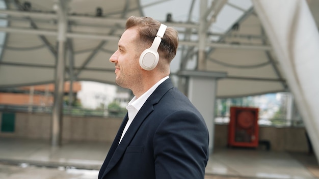 Happy business man using headphone listening relax music and move along Urbane