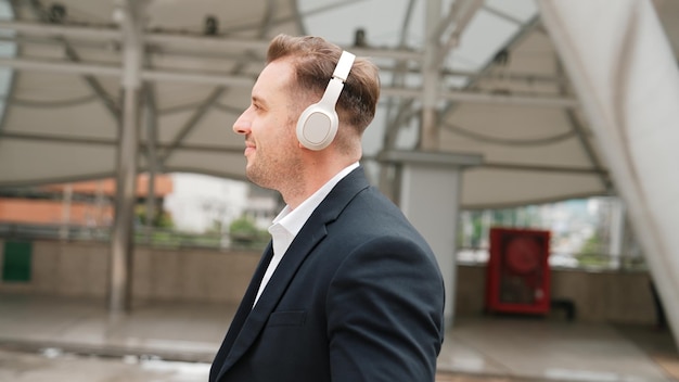 Happy business man using headphone listening relax music and move along urbane