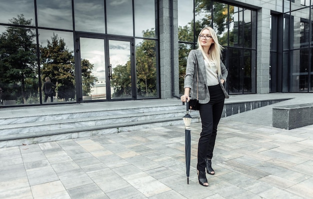 Happy business woman holding umbrella stick on the background of business office. Waiting for the rain