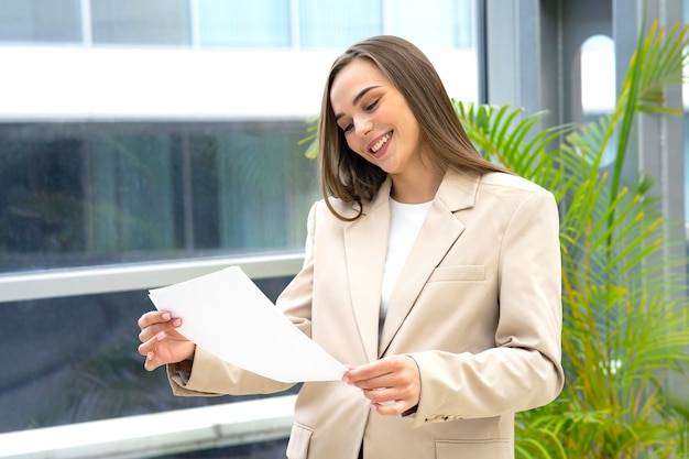 Happy business woman in the office holding documents report the girl smiles and reads the contract