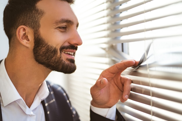 The happy businessman watching through the blinds