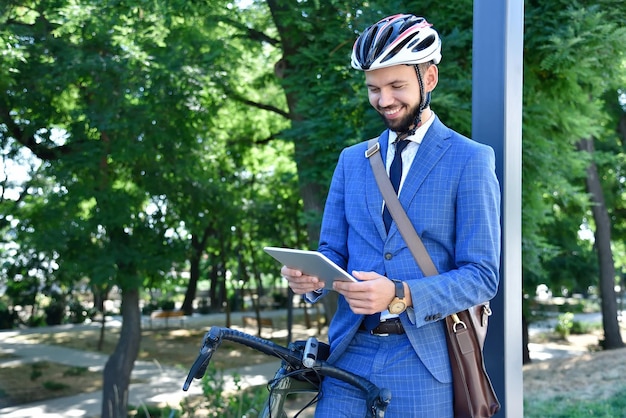 Happy businessman with bike using tablet computer