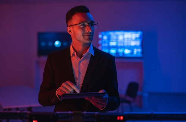 The happy businessman with a tablet working in a room with screens