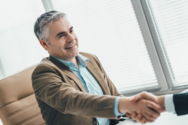 The happy businessmen handshaking in the office