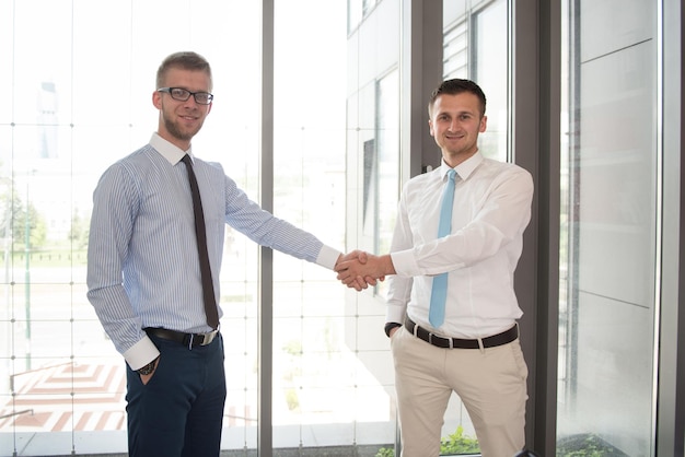 Happy Businessmen Shaking Hands While Standing In Office