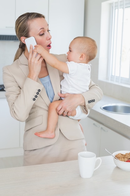 Happy businesswoman holding her baby talking on the phone