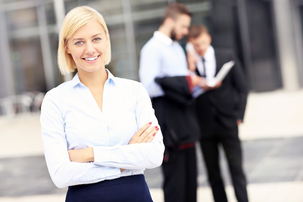 a happy businesswoman standing outside modern building