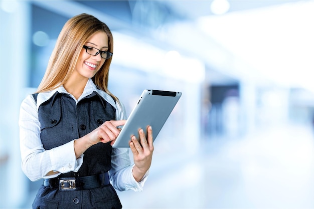 Happy businesswoman standing with table computer over gray background.