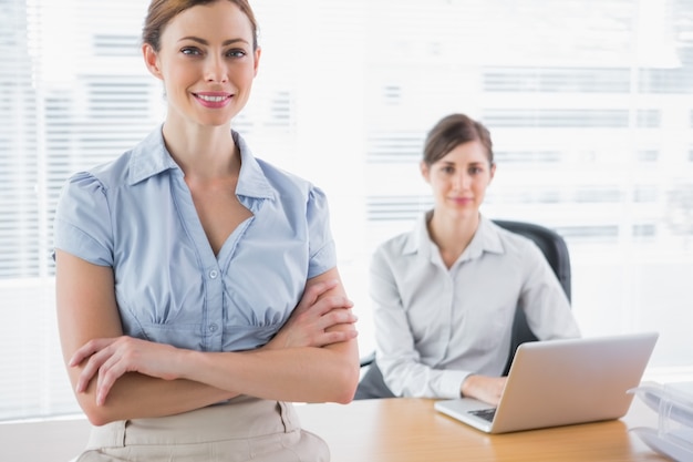 Happy businesswomen smiling at camera at their desk