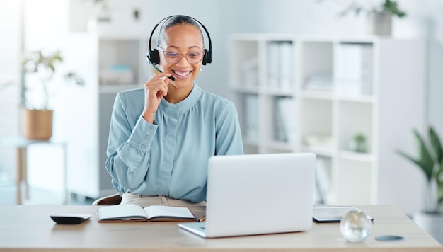 Happy call center agent calling talking and doing online sales with a laptop and modern headset inside a company office Smiling ecommerce consultant promoting services in telemarketing company