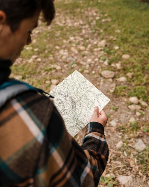 Happy camping man in the forest looking on the map