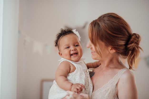 Happy candid authentic mother holding mixed race baby daughter in your arms at cozy apartment