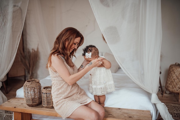 Happy candid authentic mother holding mixed race baby daughter in your arms at cozy apartment