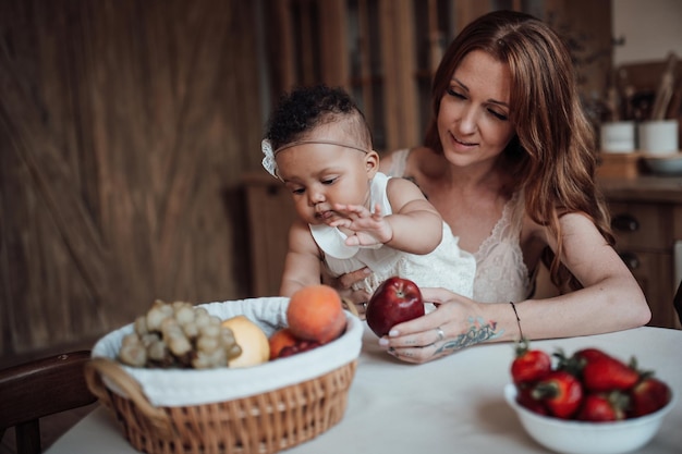 Happy candid authentic mother with mixed race baby daughter spend time together at cozy kitchen