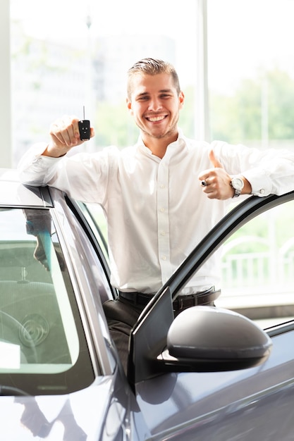 Happy car owner is showing thumbs up and his new car key