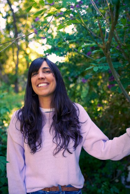 Happy carefree young woman portrait she is smiling looking at camera standing in nature