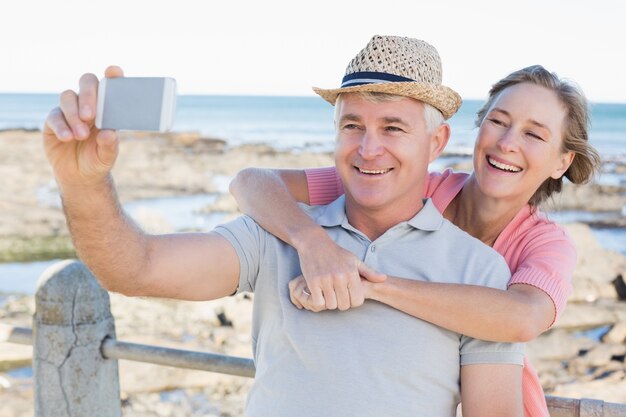 Happy casual couple taking a selfie by the coast