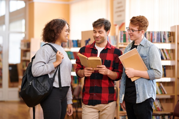 Happy casual students with books preparing for seminar or exam and discussing tasks or questions