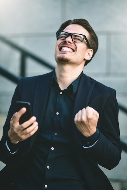 Happy caucasian businessman in glasses dressed at classic wear standing at the street.