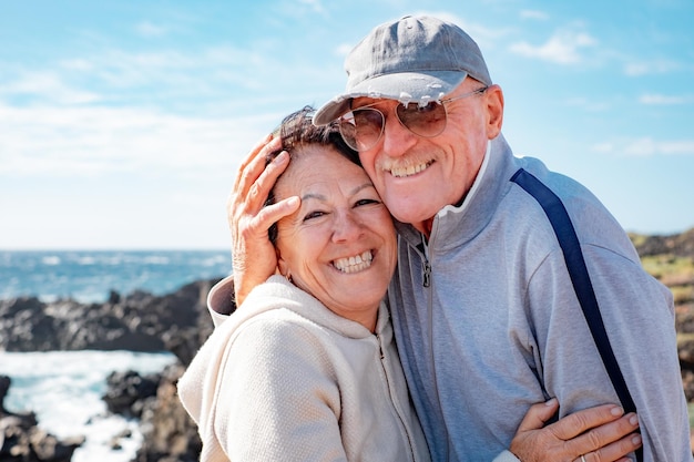 Happy caucasian senior couple hugging with tenderness enjoying sunny day in sea excursion