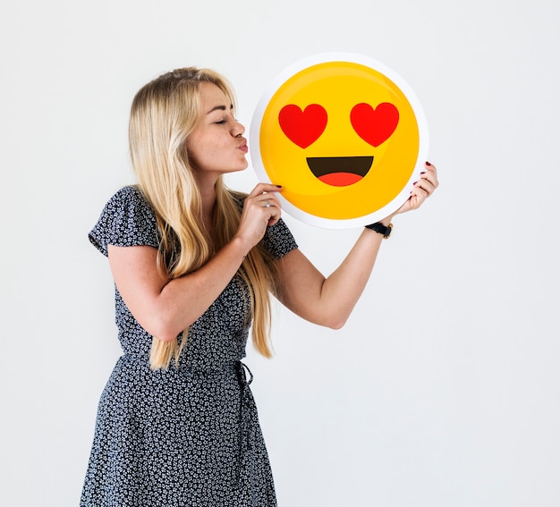 Happy Caucasian woman holding falling in love emoticon love and relationship concept