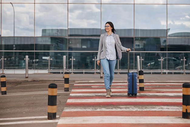 Happy caucasian woman traveller in airport terminal with luggage