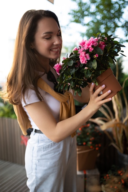 Happy caucasian young woman chooses potted flowers to buy at outdoor garden stall