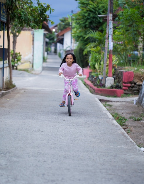 Happy cheerful asian child girl riding a bicycle