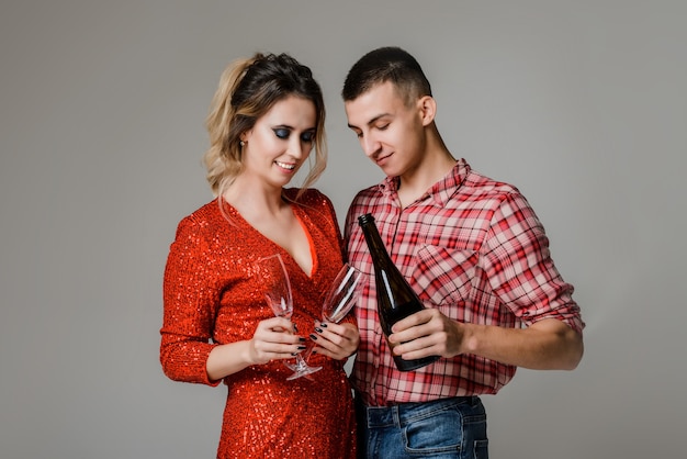 Happy cheerful couple celebrating new year holding glasses with champagne over gray