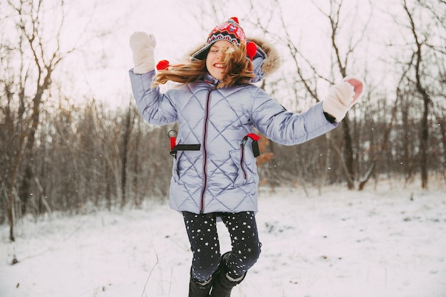 Happy cheerful little girl having fun in the forest on a winter day. child plays with snow.