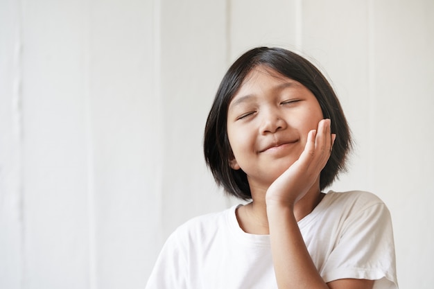 Happy cheerful little girl on white wall with soft light display in fresh morning time 