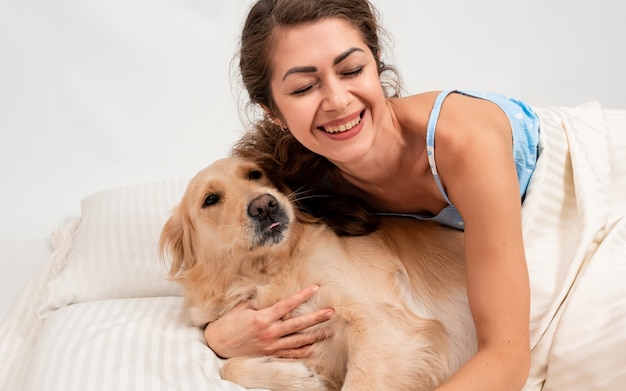 Happy cheerful smile woman playing and hugging with her dog on bed at home