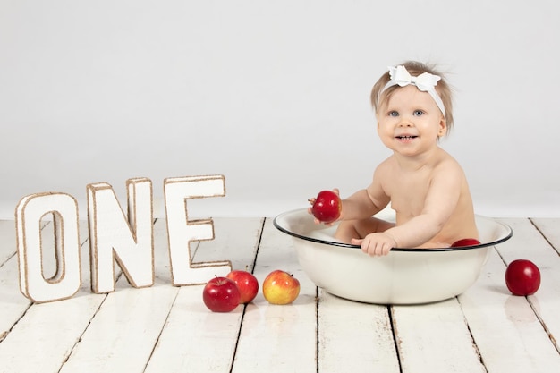 A happy child bathes in a basin Beautiful little girl in one year Little one with letters