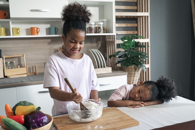 Happy child black skin thresh flour in kitchen