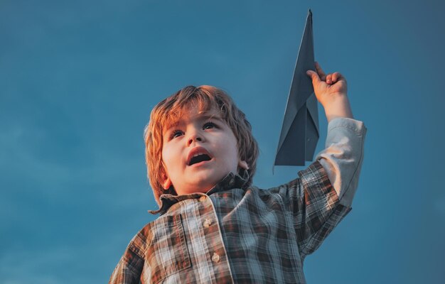 Happy child boy running on meadow with toy airplane in summer in nature little cute boy playing with