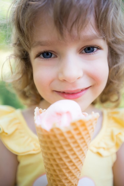 Happy child eating ice cream outdoors in summer park