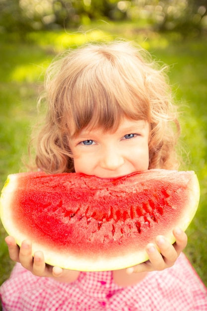 Happy child eating watermelon. Kid having picnic in autumn park