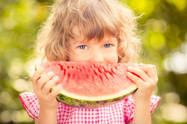 Happy child eating watermelon. Kid having picnic in autumn park