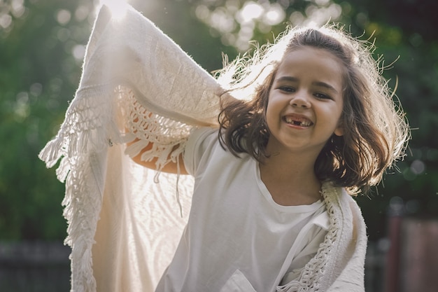 Happy child. Funny girl playing with a blanket. Smiling child girl. Cheerful child outdoors in nature